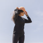 White Sands - Women's Long-Sleeve Hooded Henley in Obsidian (Black), person standing in a mountainous landscape.