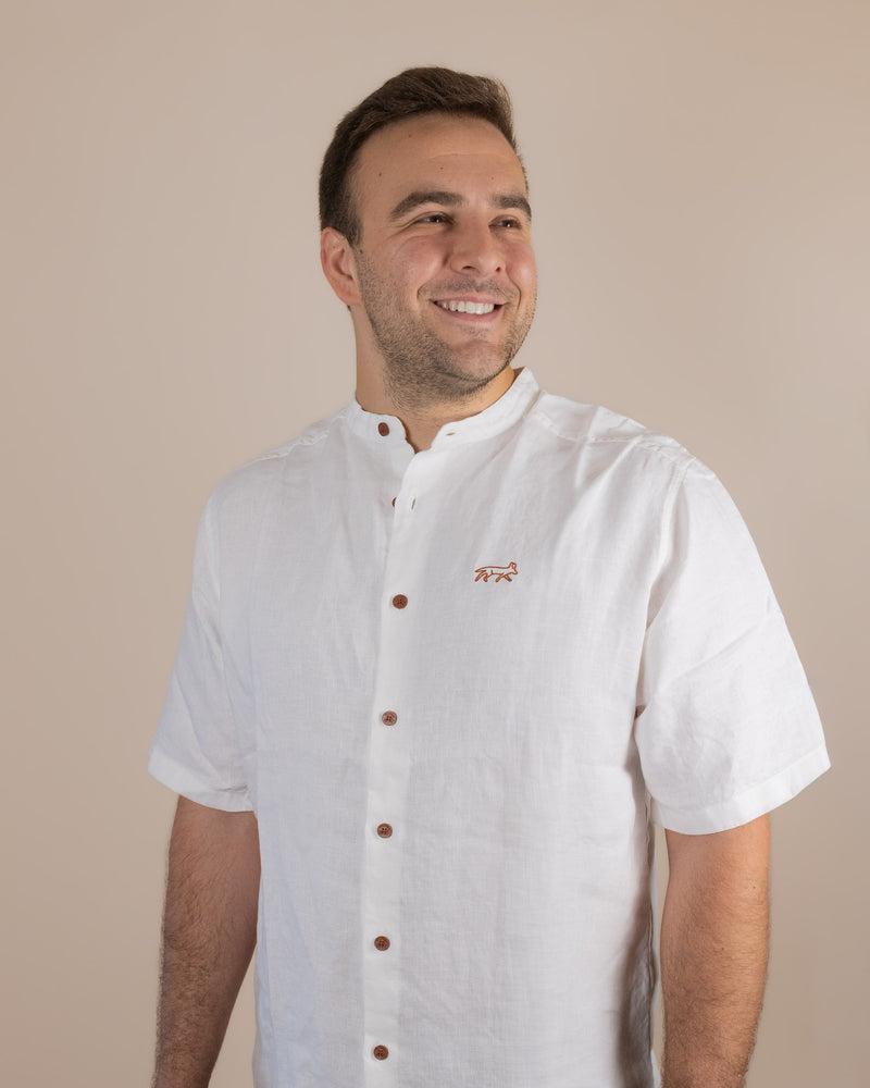 Man wearing a white chef's coat with brown buttons on a beige background