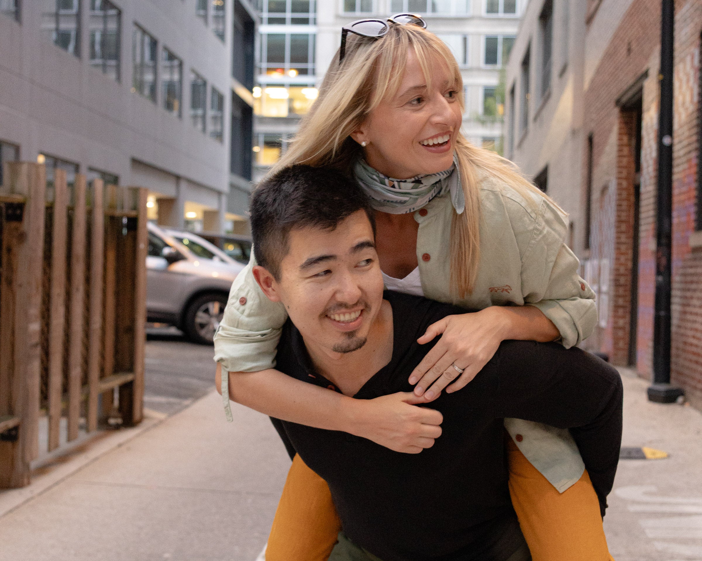 Man giving a woman a piggyback ride on a city street.