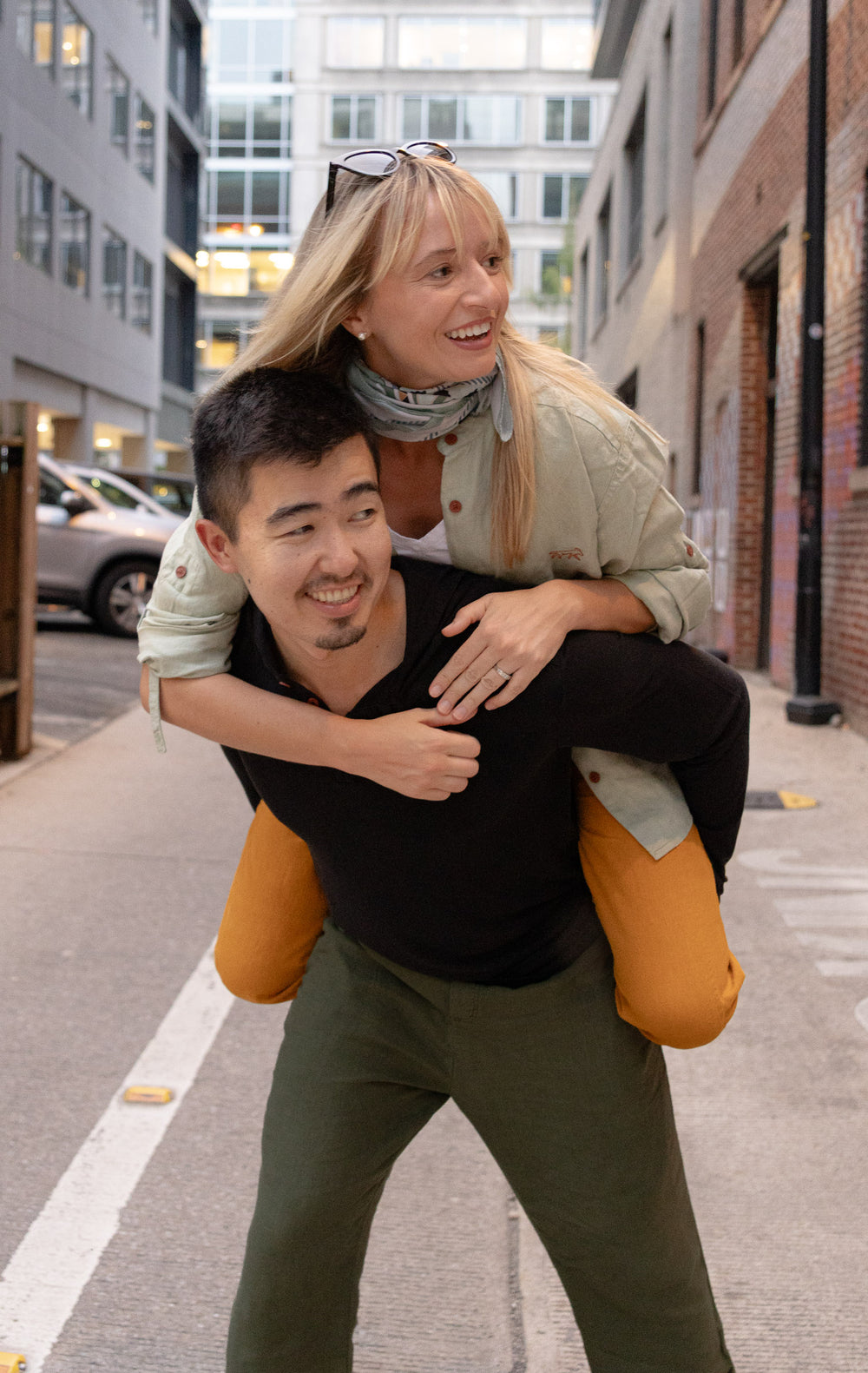 Man giving a woman a piggyback ride on a city street.