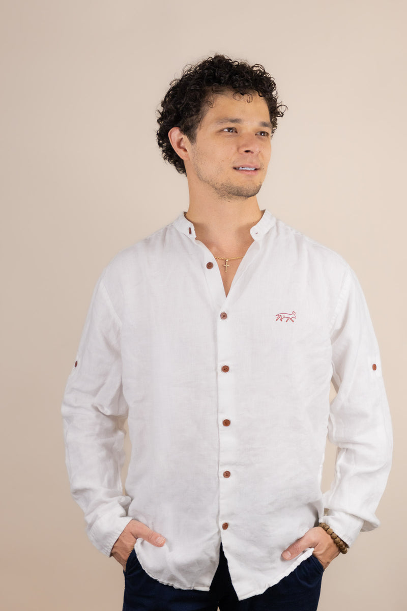 Man wearing a white button-up shirt with brown buttons against a beige background